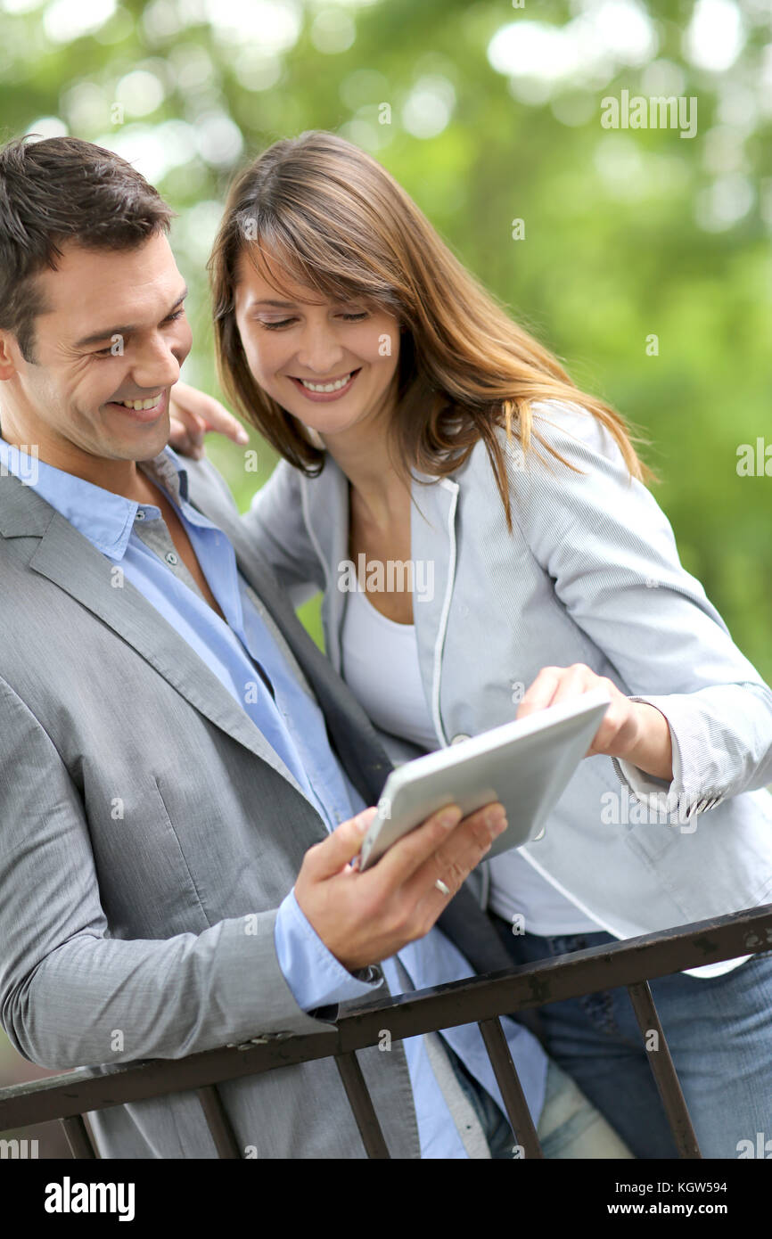 Couple standing in park with electronic tablet Stock Photo