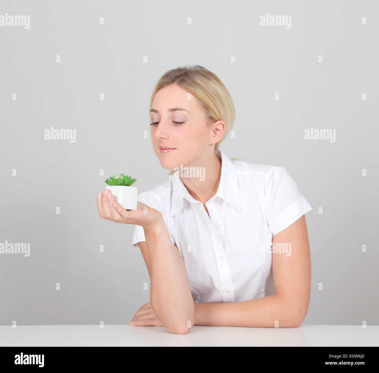 Beautiful blond woman holding plant pot Stock Photo - Alamy