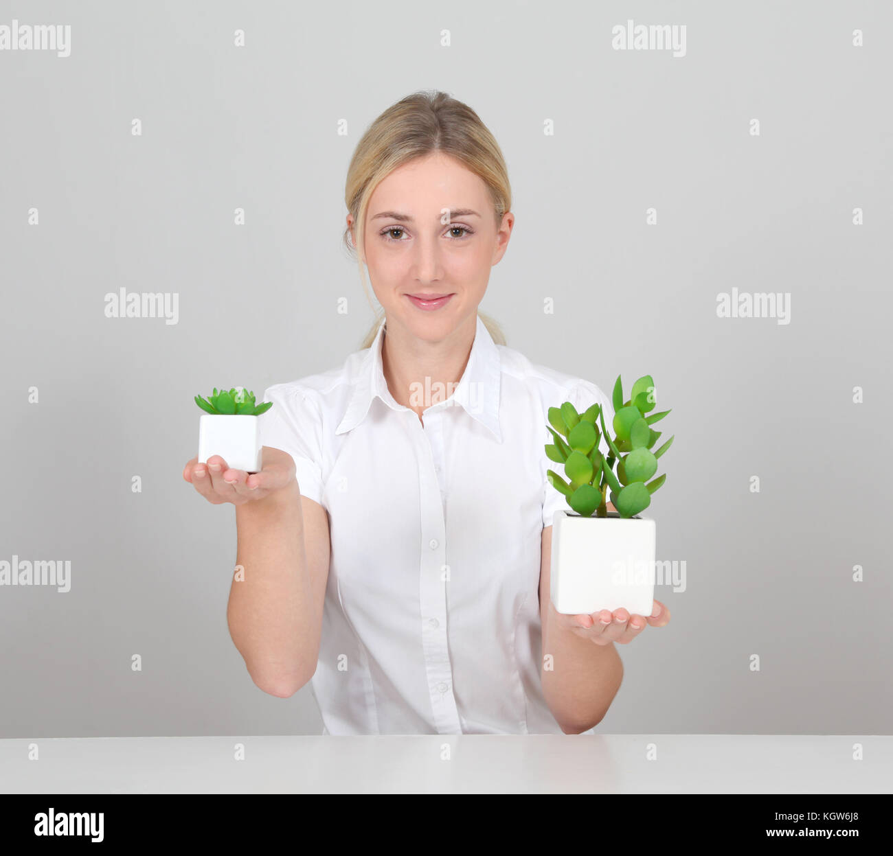 Woman holding green plant on white background Stock Photo - Alamy