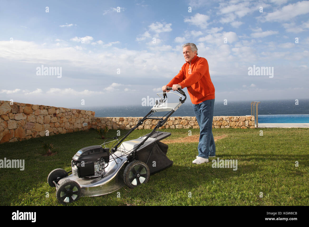 Senior man mowing the lawn Stock Photo