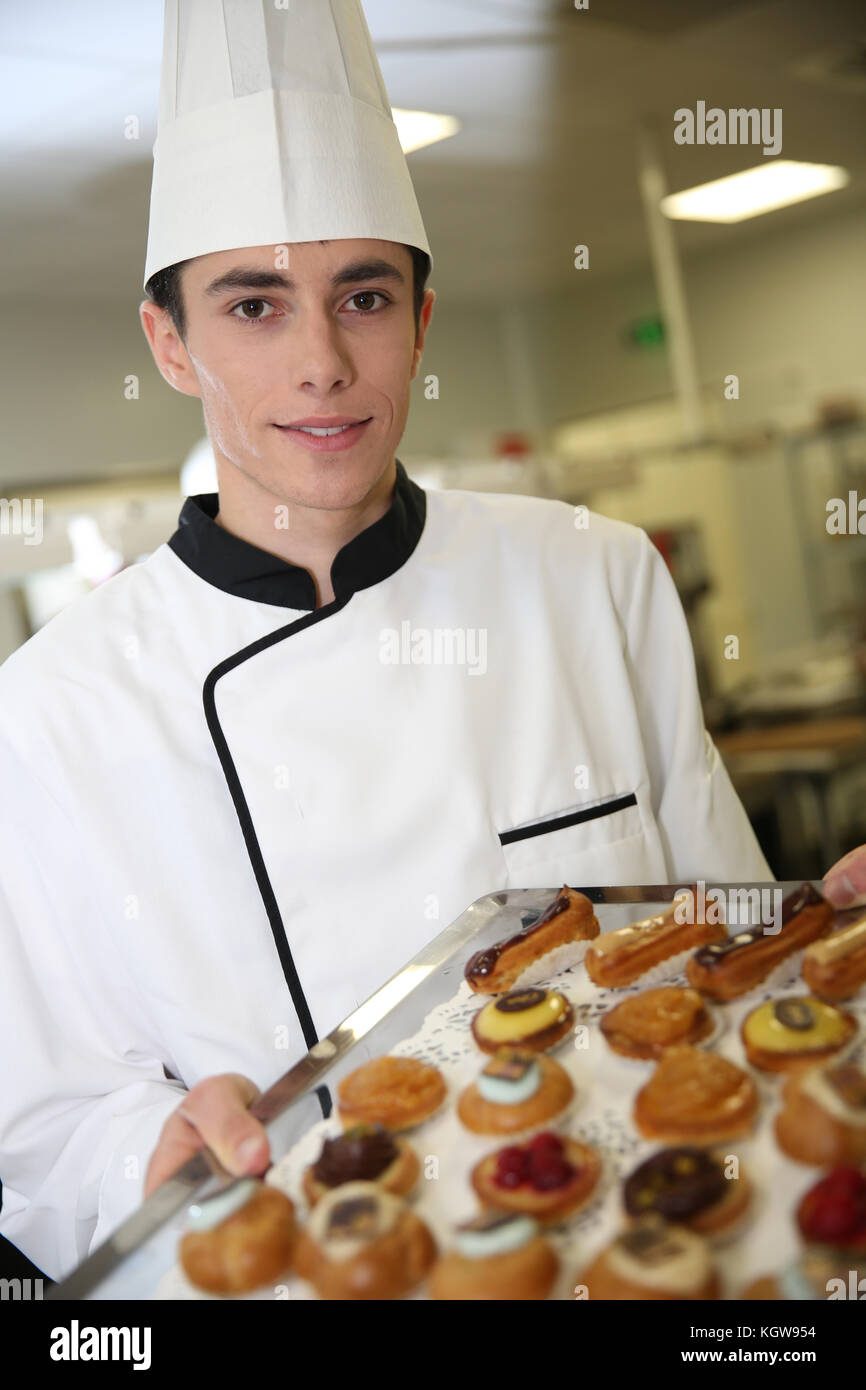 Young pastry cook holding tray of pastries Stock Photo Alamy