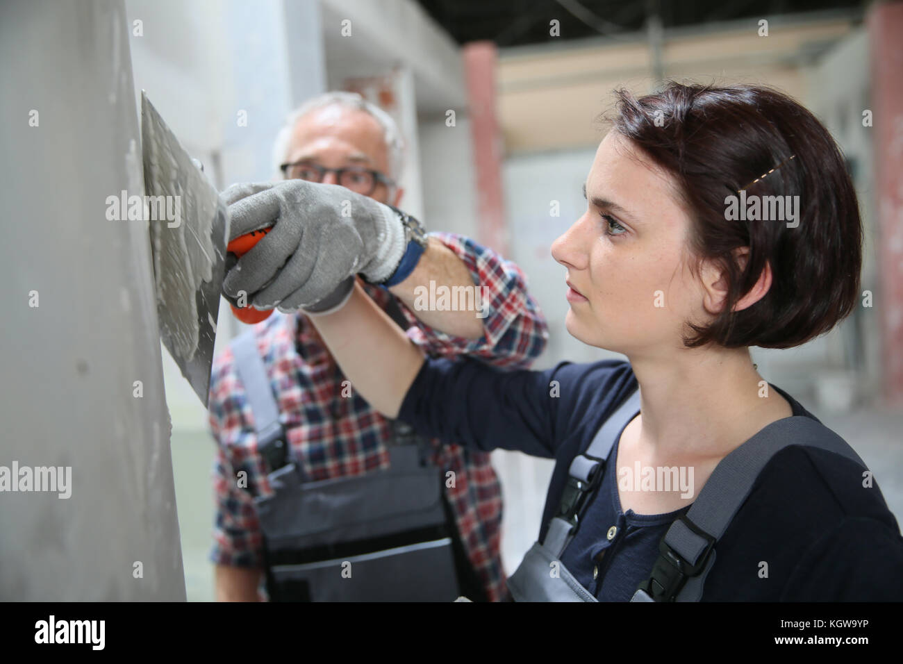 Young apprentice with professional plasterer Stock Photo