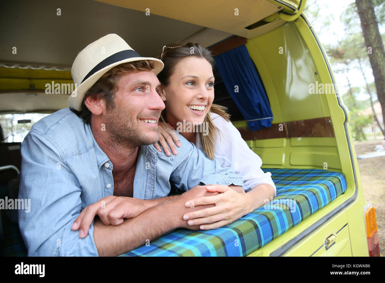Cheerful young couple laying on a camper van Stock Photo - Alamy