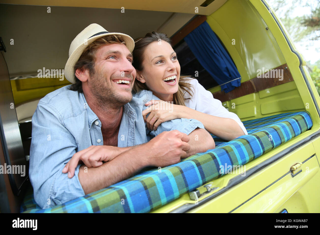 Cheerful young couple laying on a camper van Stock Photo - Alamy