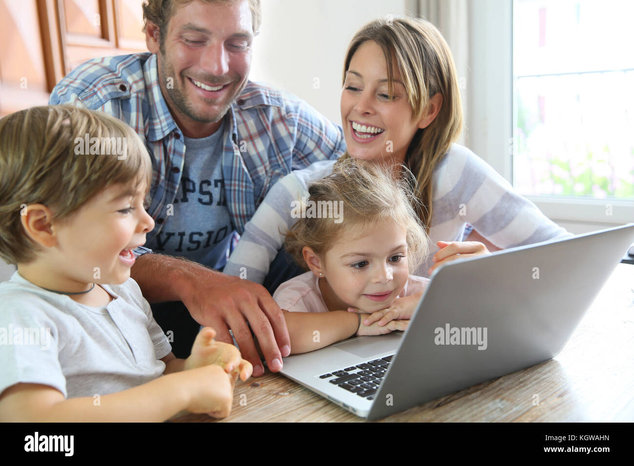 Parents Using Computer Parents with kids at home using laptop computer Stock Photo - Alamy