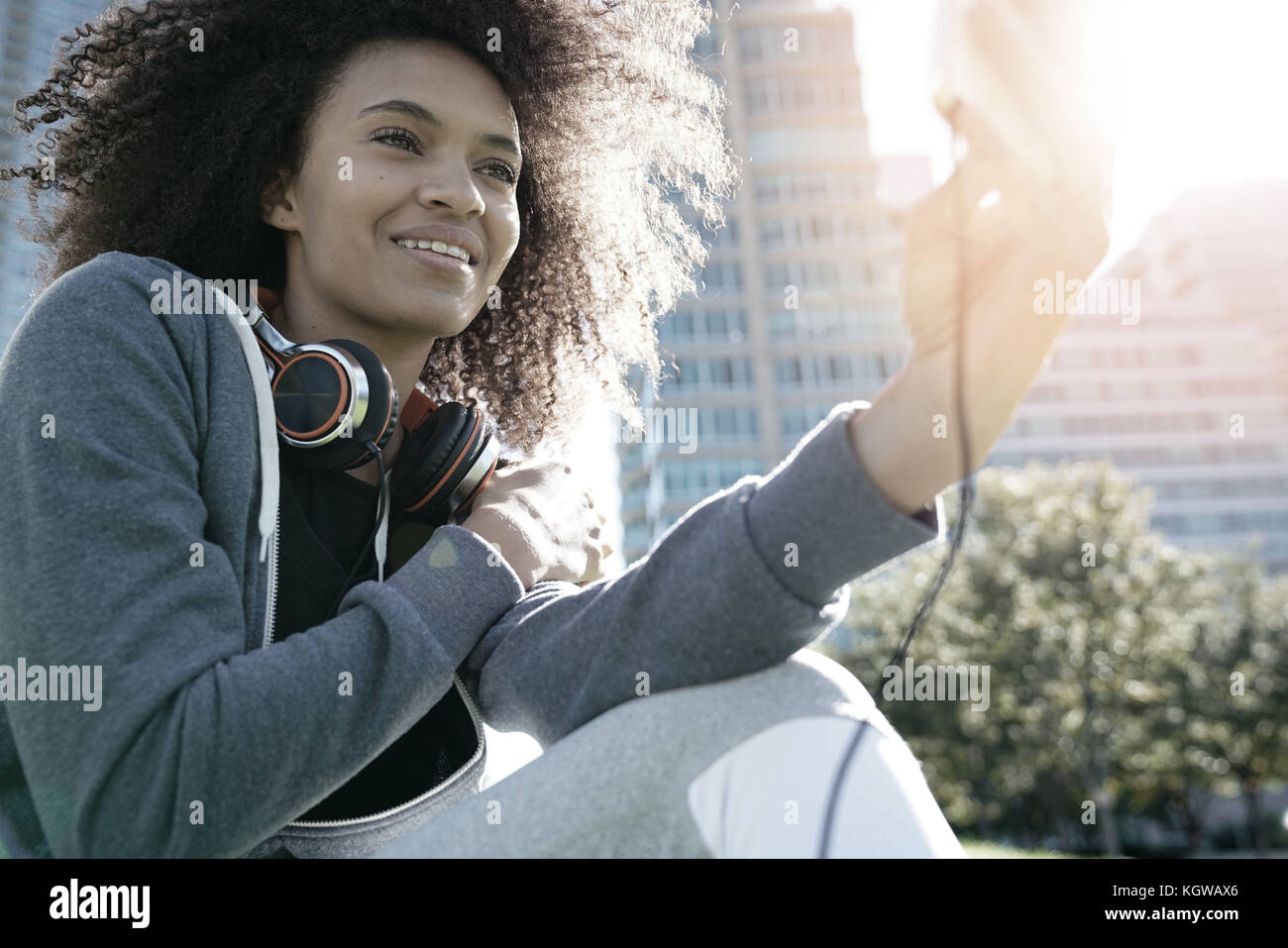 Portrait of mixed race girl in park listening to music on smartphone Stock Photo