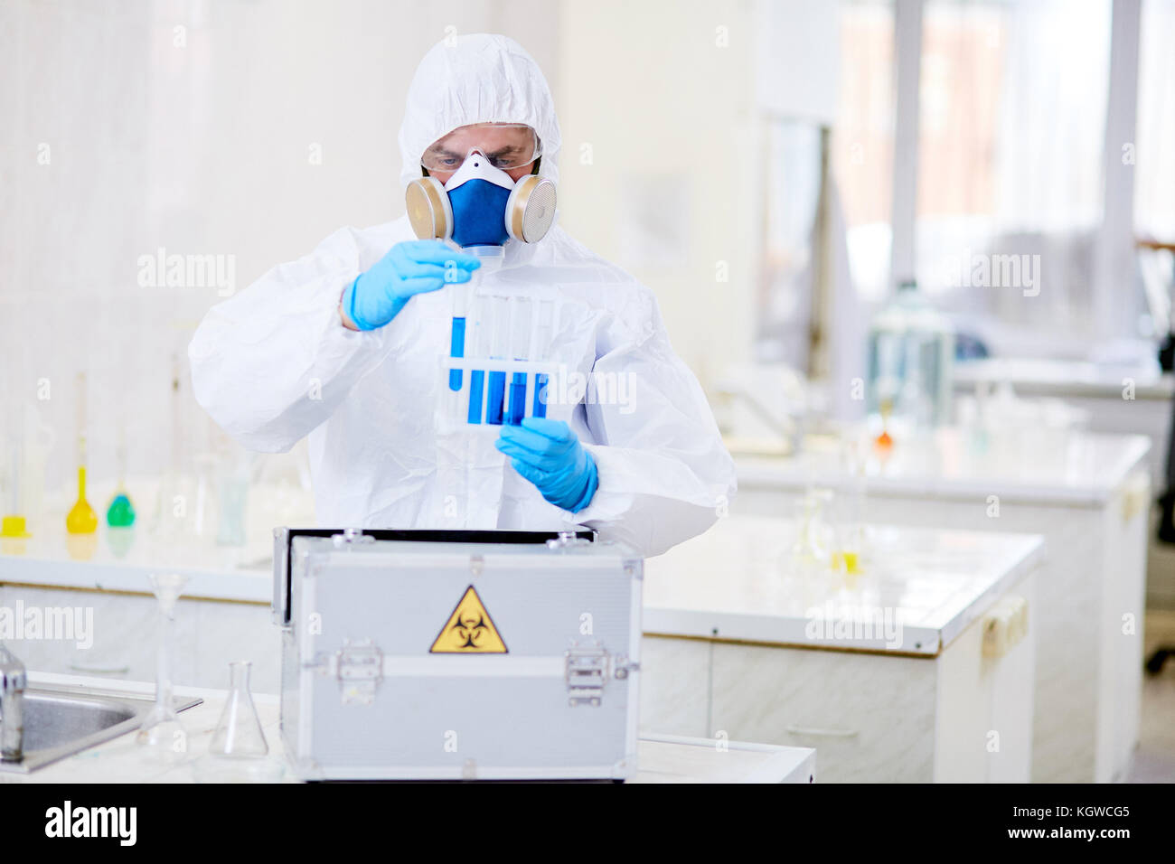 Man in coverall, gloves and respirator working with toxic liquids Stock Photo