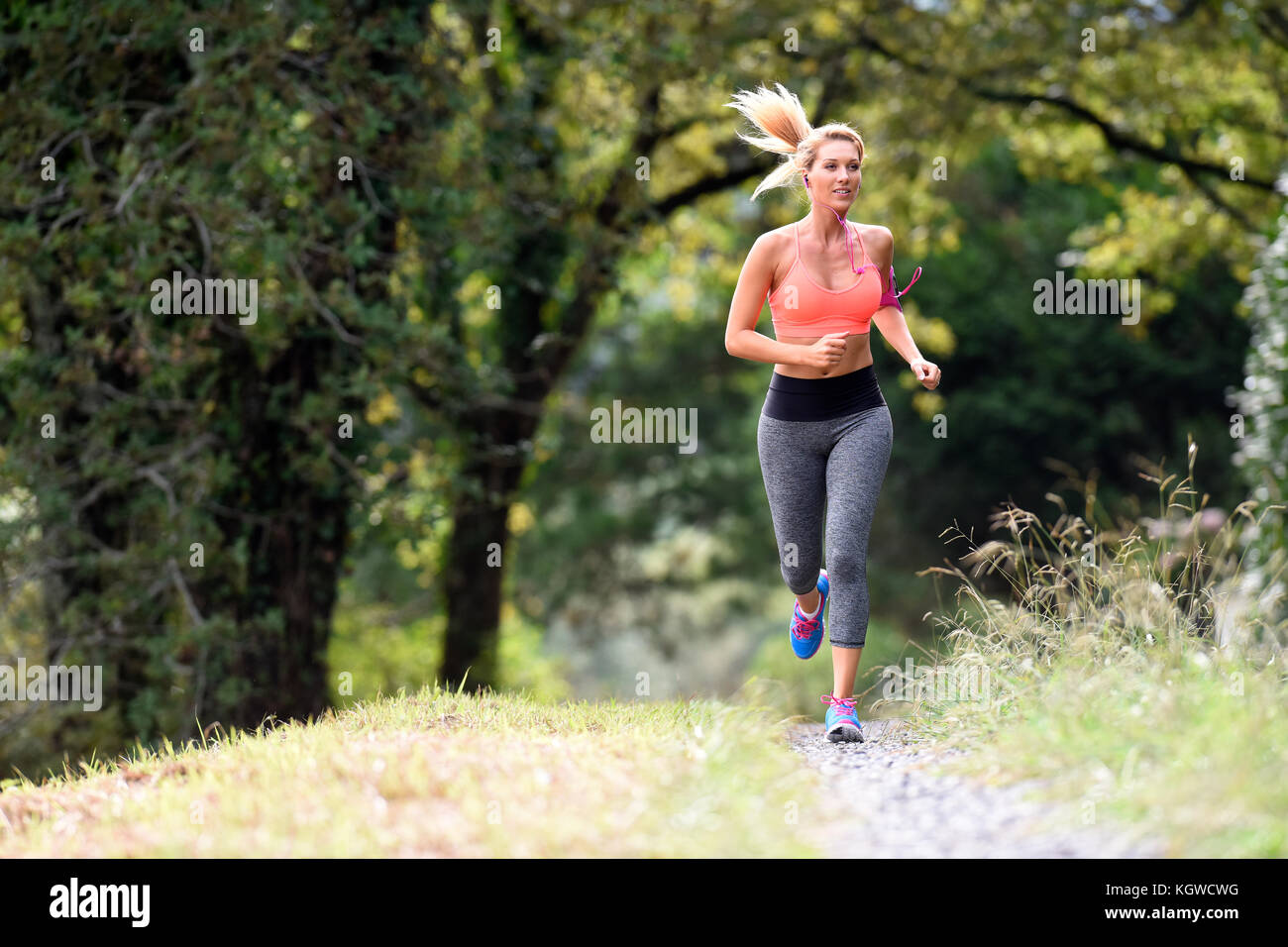 Beautiful athletic woman running in forest Stock Photo - Alamy
