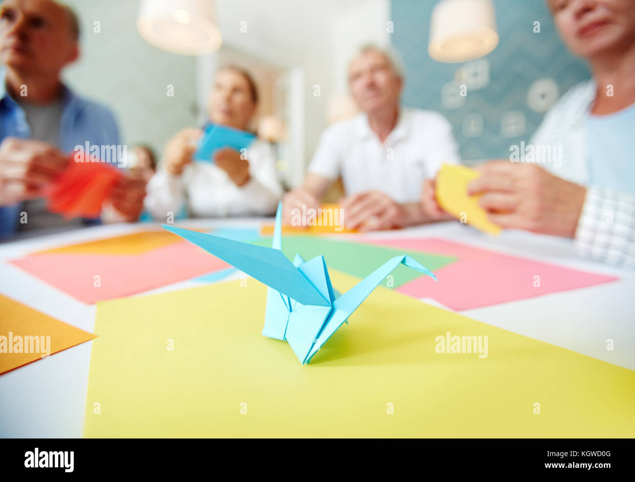 Several Humans Learning How To Make Paper Origami With Blue