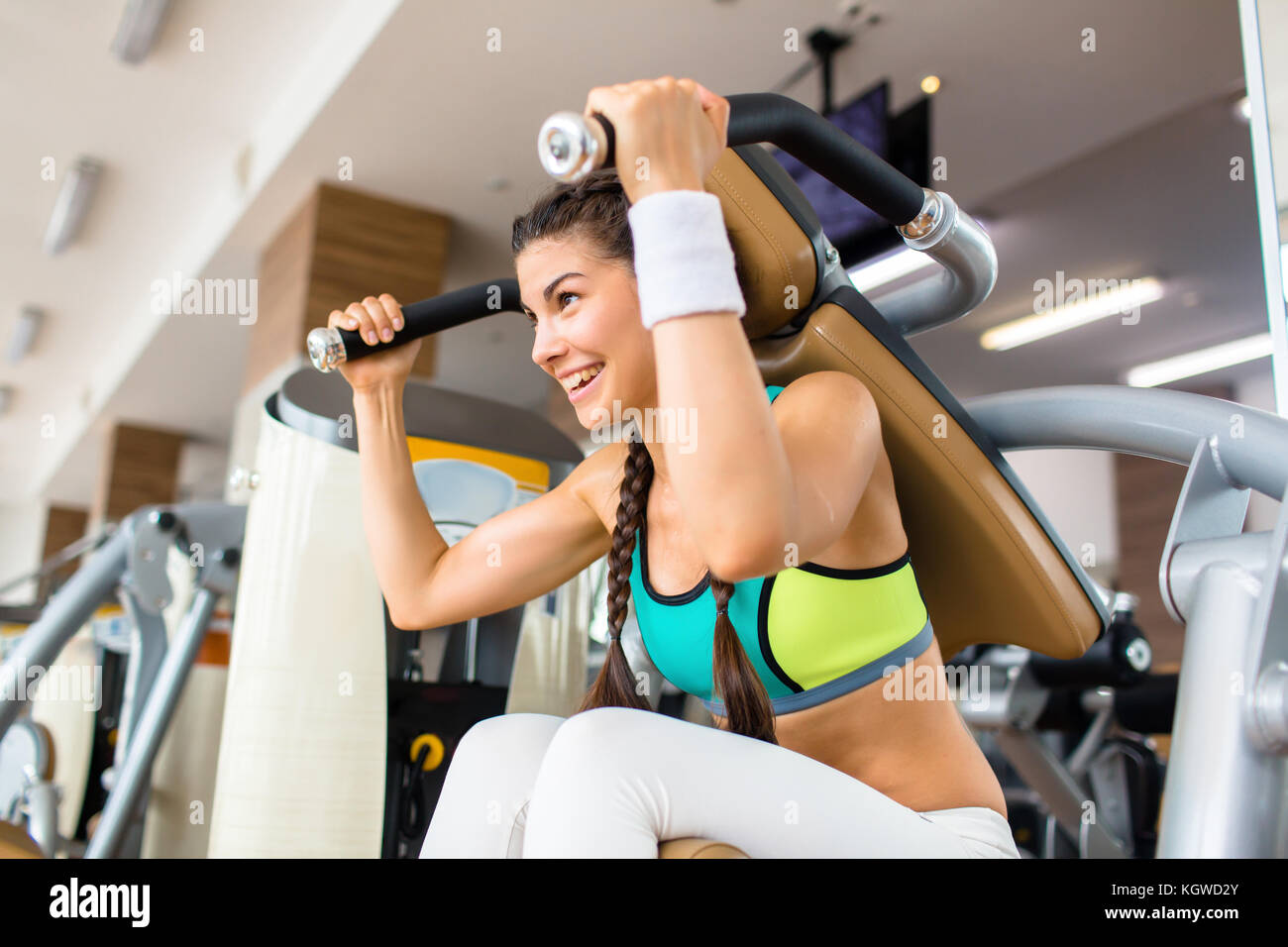 Smiling girl doing sit-ups on sports equipment in modern gym Stock ...