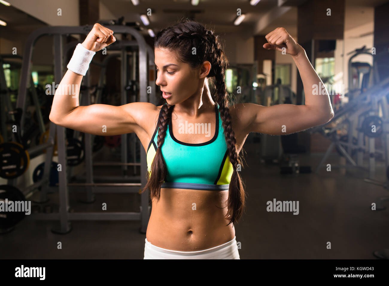 Active muscular girl looking at one of her arms in sports club Stock Photo  - Alamy