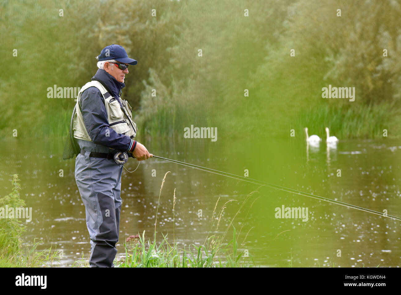 Fly-fisherman fishing in river from riverbanks Stock Photo