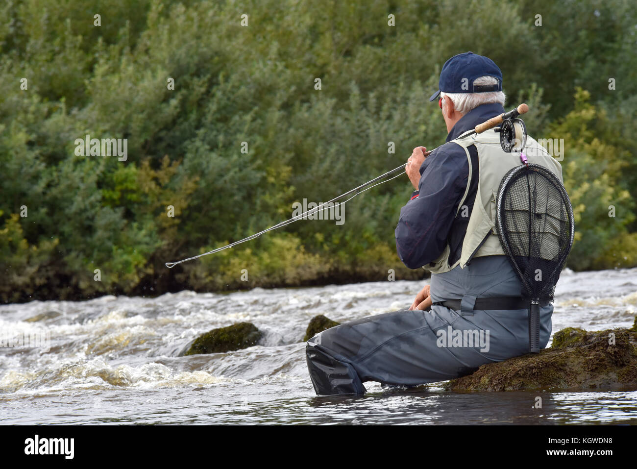 Fly-fisherman waiting with fishing pole on shoulder Stock Photo