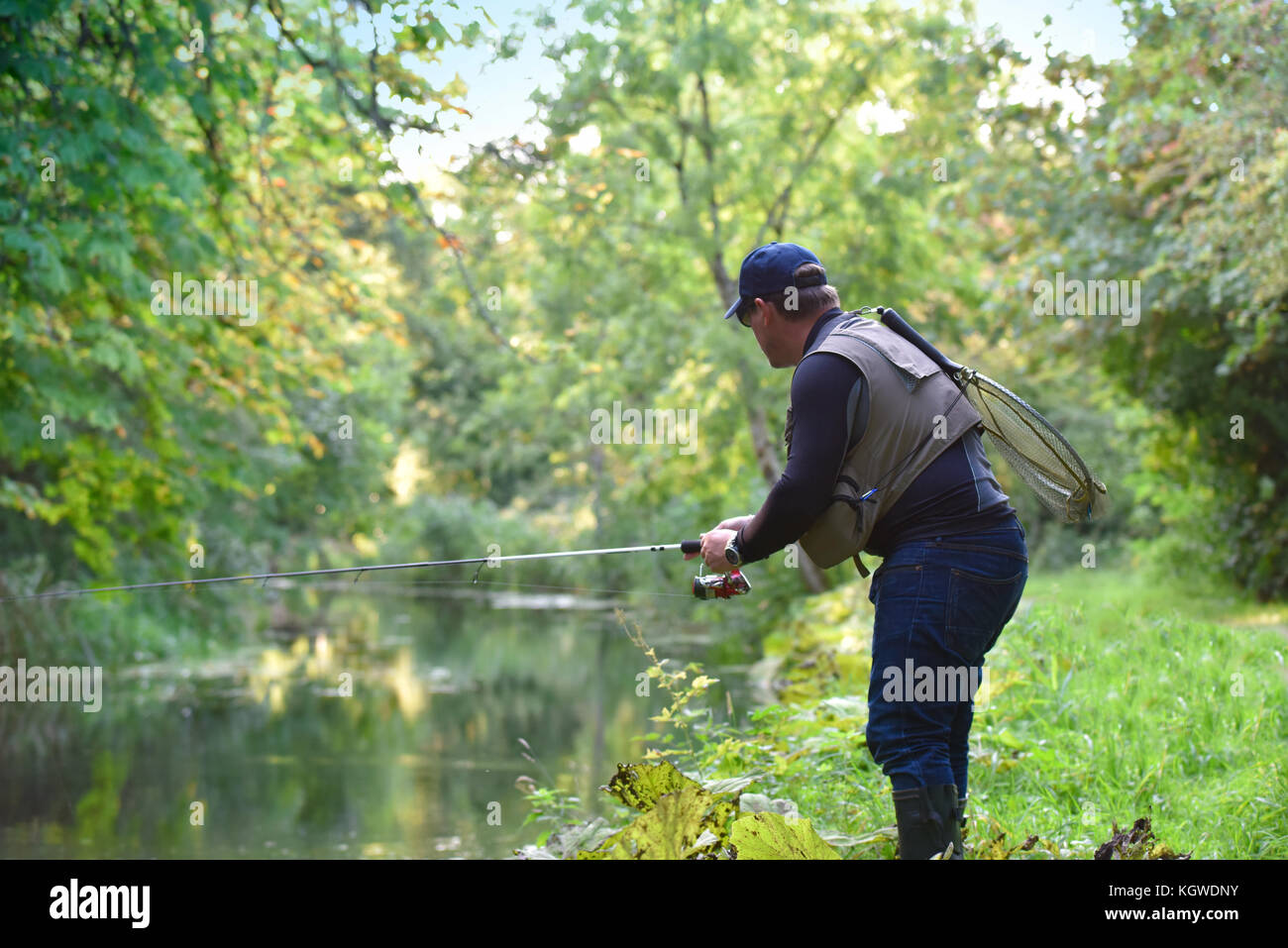 Fisherman fishing in river from riverbanks Stock Photo