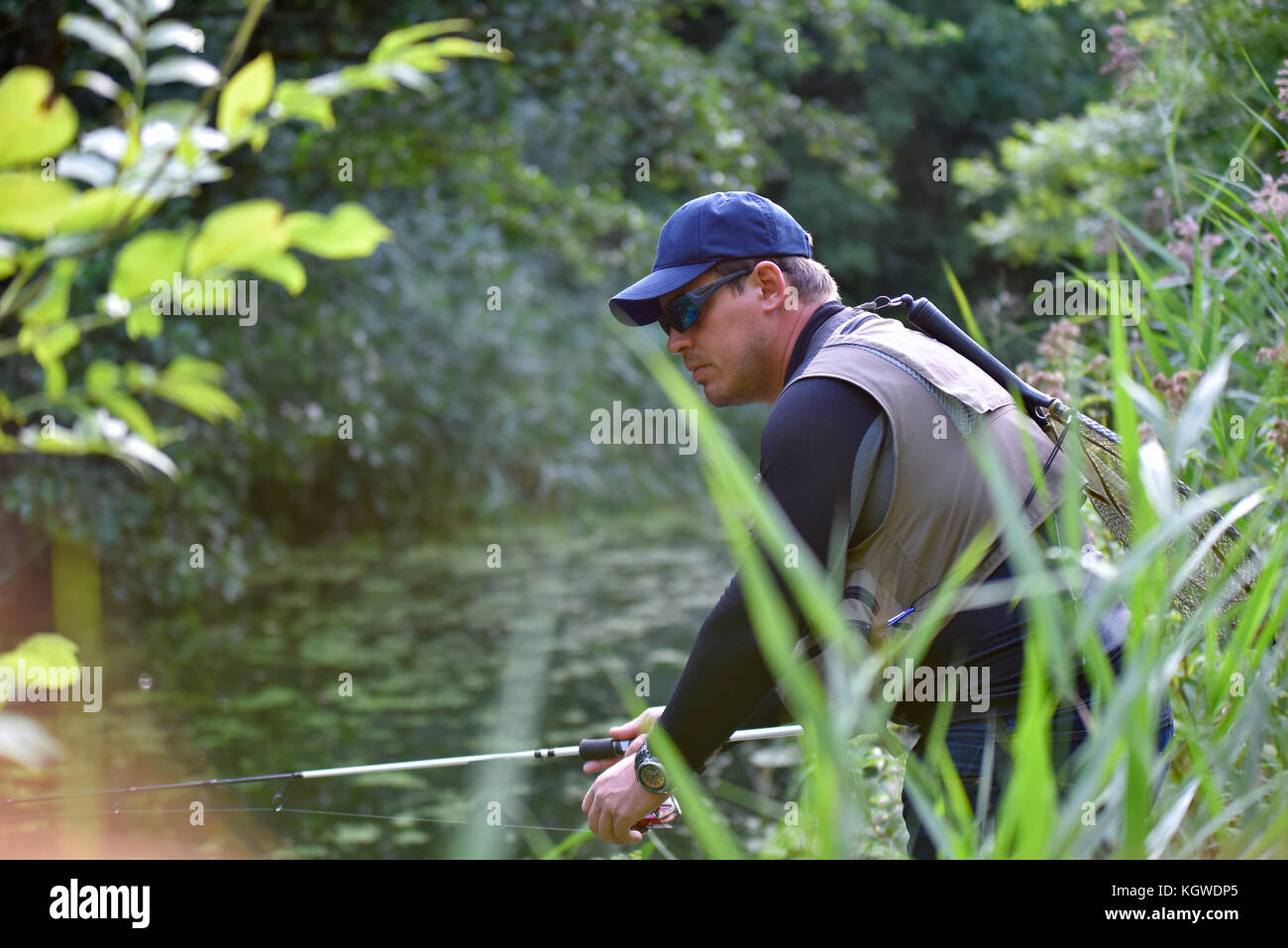 Fisherman fishing in river from riverbanks Stock Photo