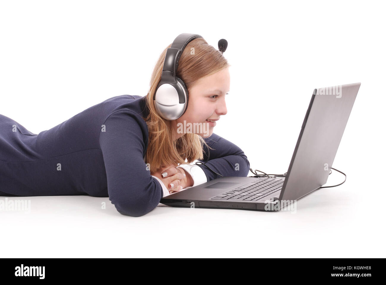 Pretty young teenage girl with laptop lying on the floor and headphones ...