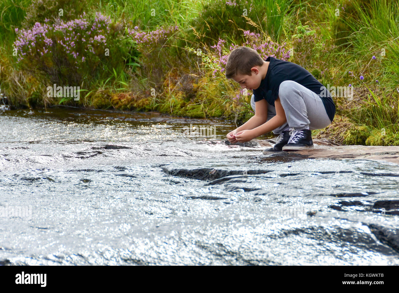 A 10 year old kid looking for seashells  in Gairloch on the Atlantic Coast of Scotland in Wester Ross Stock Photo