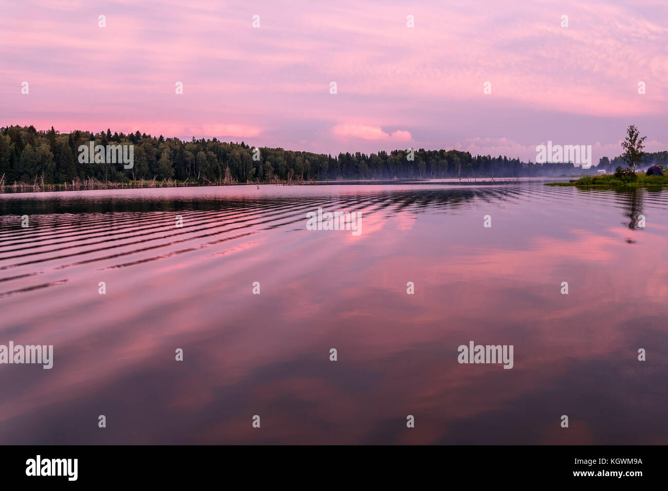 Scenic delicate pink sunset on the lake with beautiful clouds and trees ...