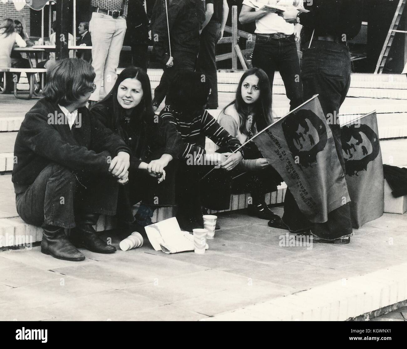 Two male students and two female students all wearing hippie attire sit together and talk on a set of steps, with two students holding flags with the face of revolutionary Che Guevara, during an anti Vietnam War student sit-in protest at North Carolina State University, Raleigh, North Carolina, 1970. () Stock Photo