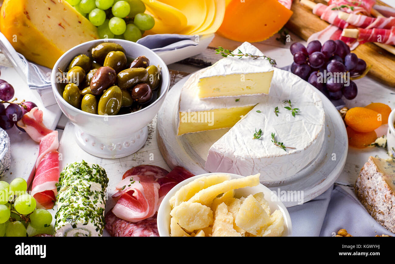 Charcuterie assortment, cheeses, olives and fruits on a white wooden