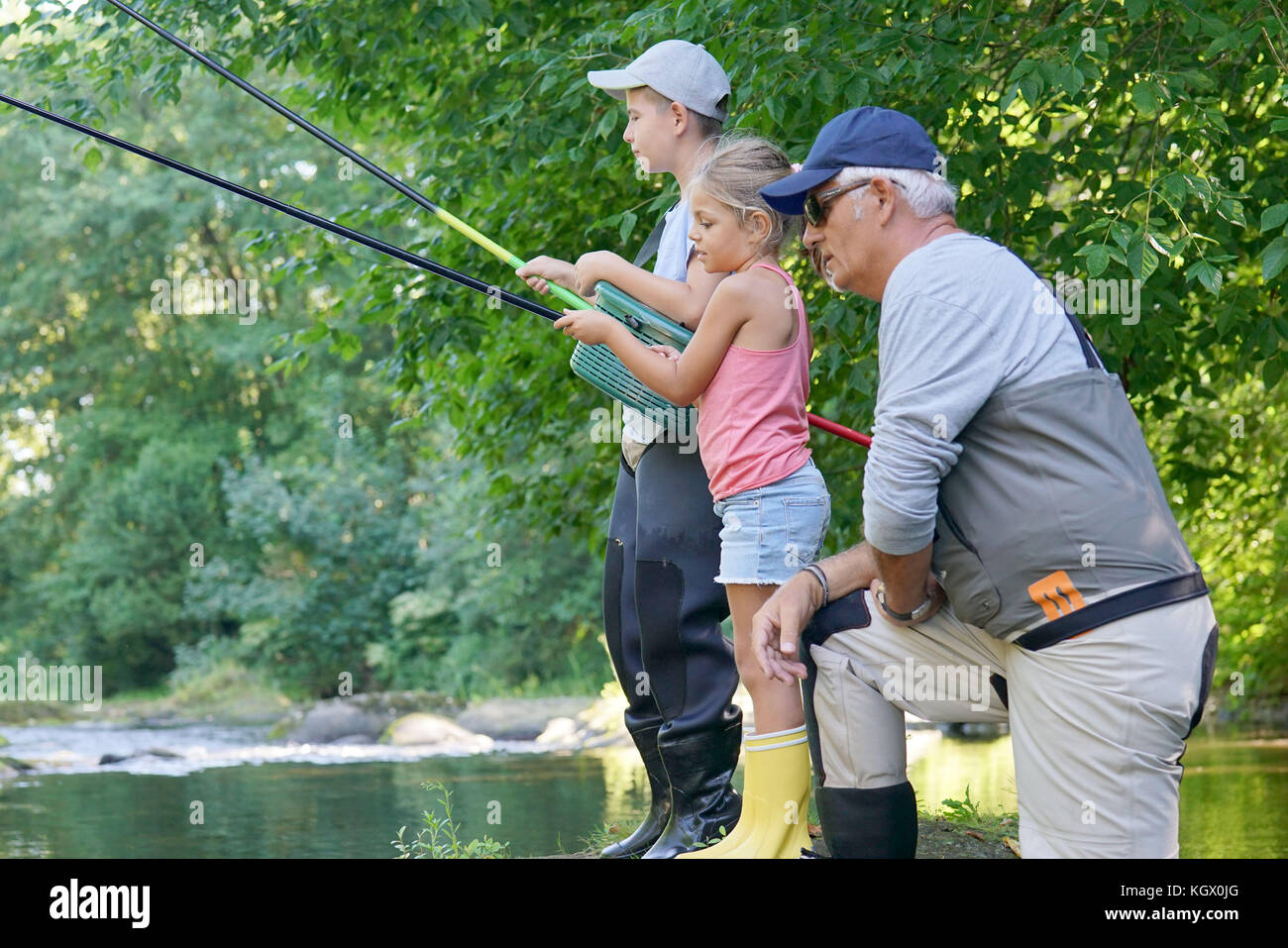 Dad teaching kids how to fish in river Stock Photo - Alamy