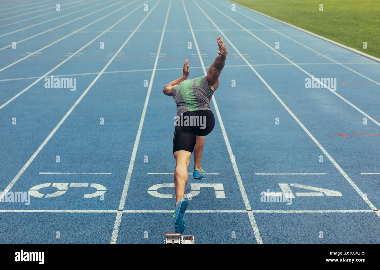 Rear view of an athlete starting his sprint on an all-weather running ...