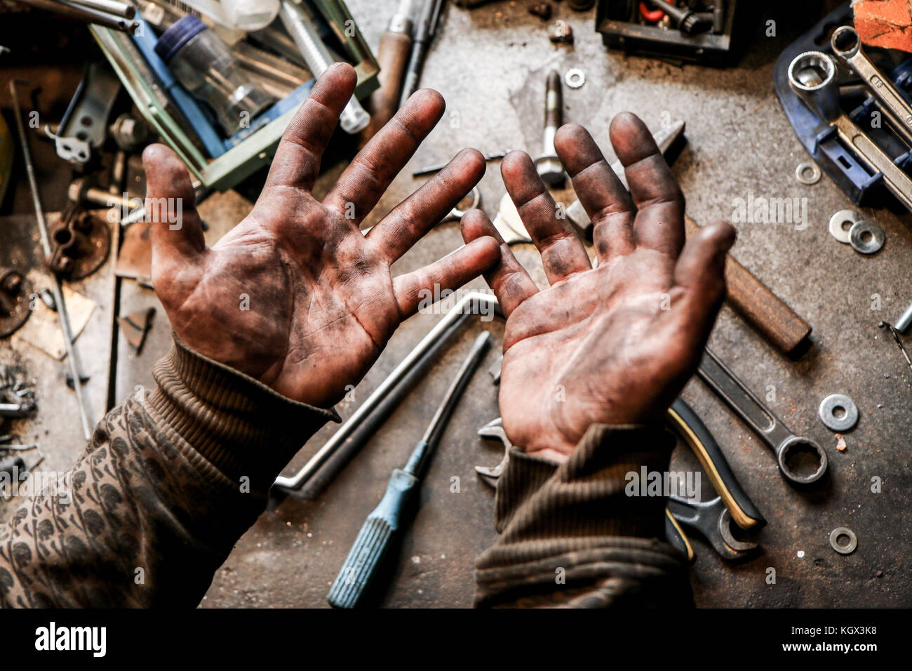 A picture of dirty hands of a guy from the garage. Hard and dirty work is behind him. Stock Photo