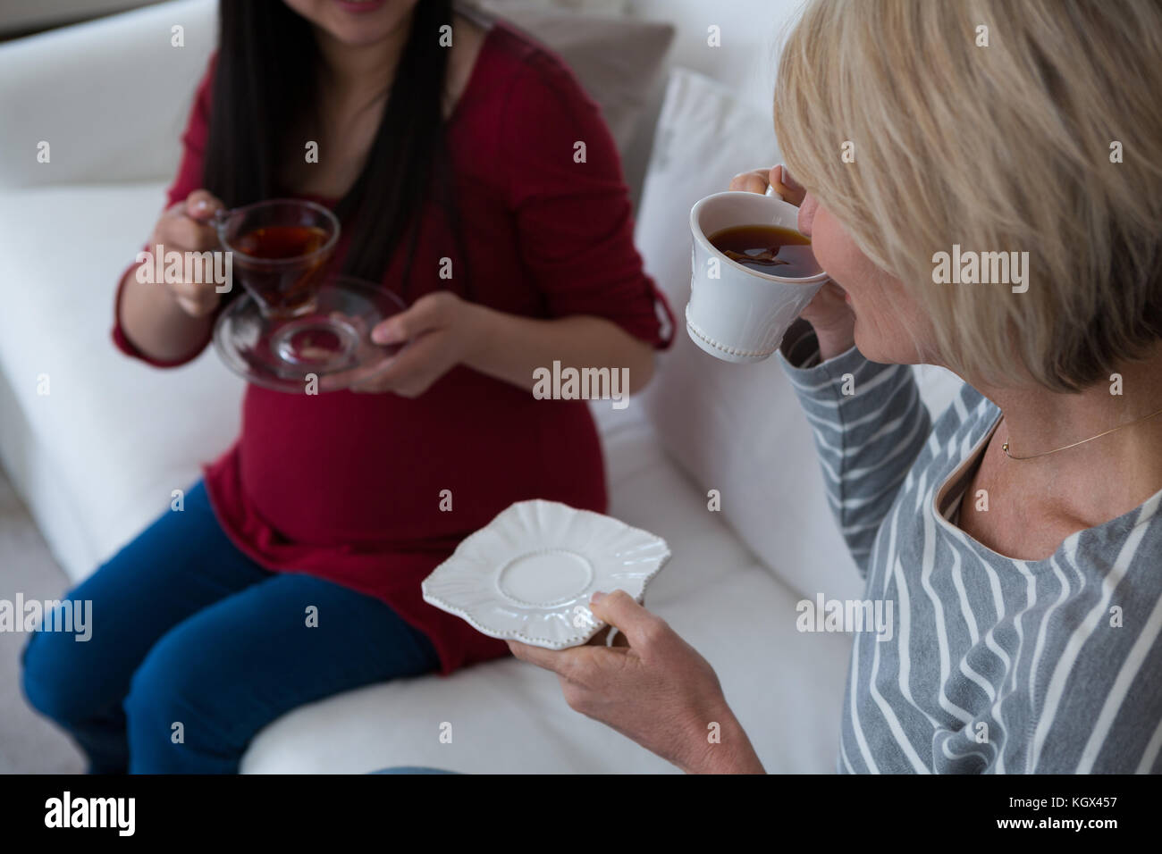 Female friends having tea in living room at home Stock Photo