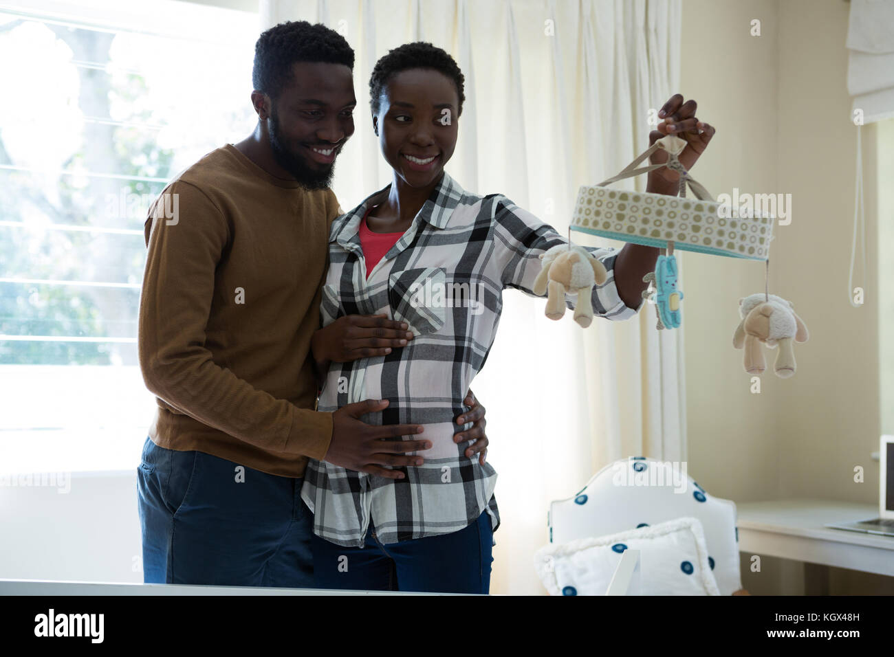 Happy man and pregnant woman holding a toy at home Stock Photo