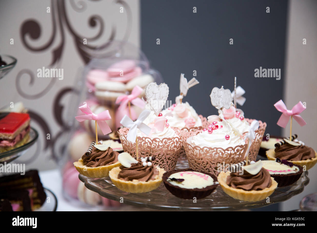 Close-up photo of cupcakes placed on a glass stand on a dessert table at  wedding reception, pink-brown color palette Stock Photo - Alamy, image size:1300x956