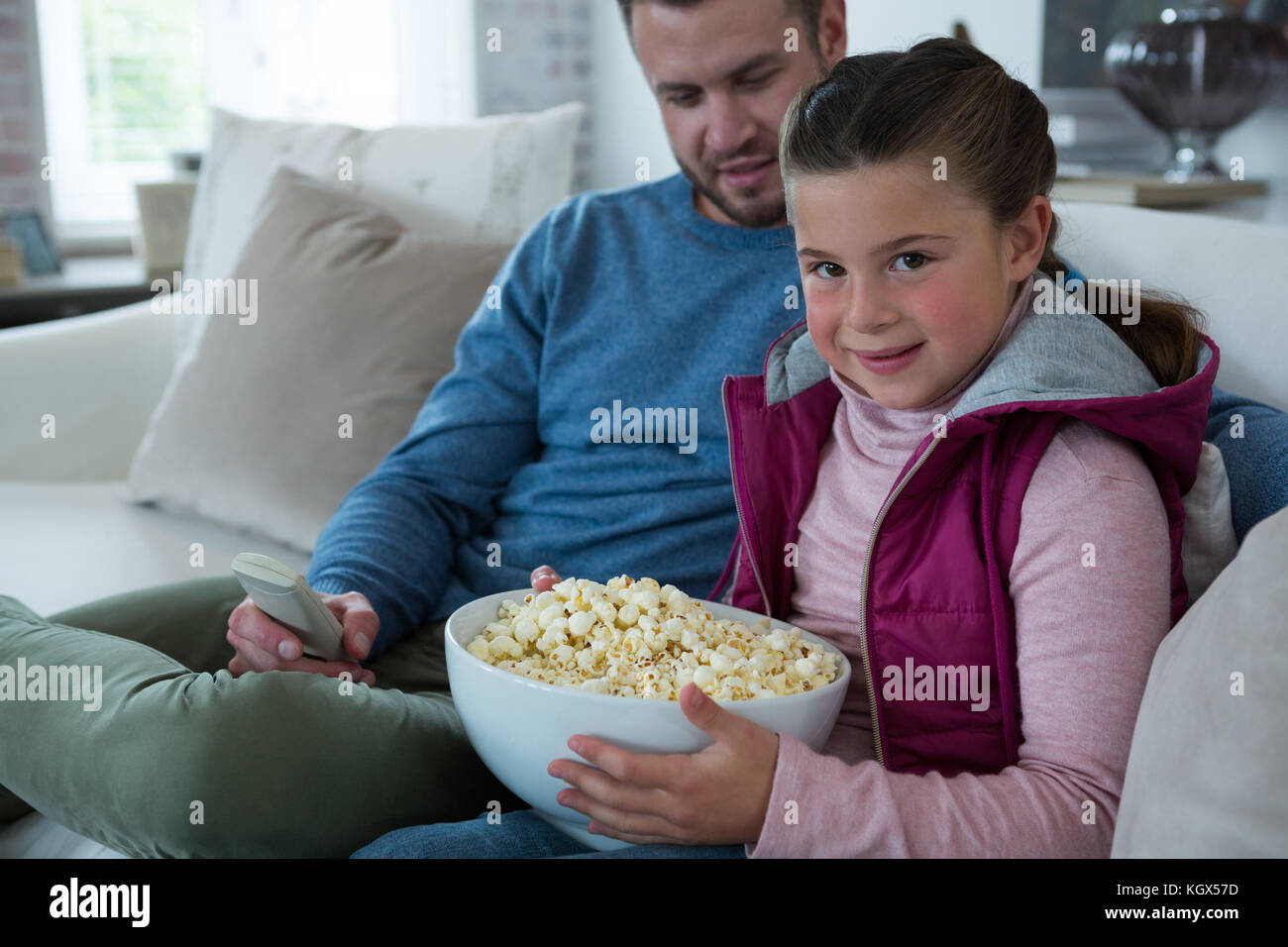 Cute Girl Holding Bowl Full Of Popcorn In Living Room Stock