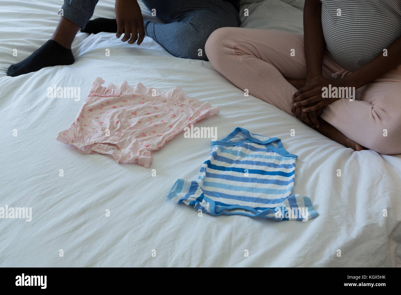 Couple looking at baby clothes in bedroom at home Stock Photo