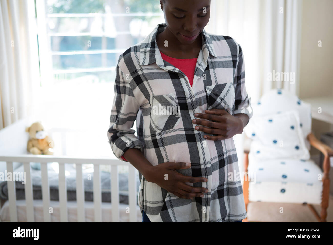 Pregnant woman touching her stomach at home Stock Photo