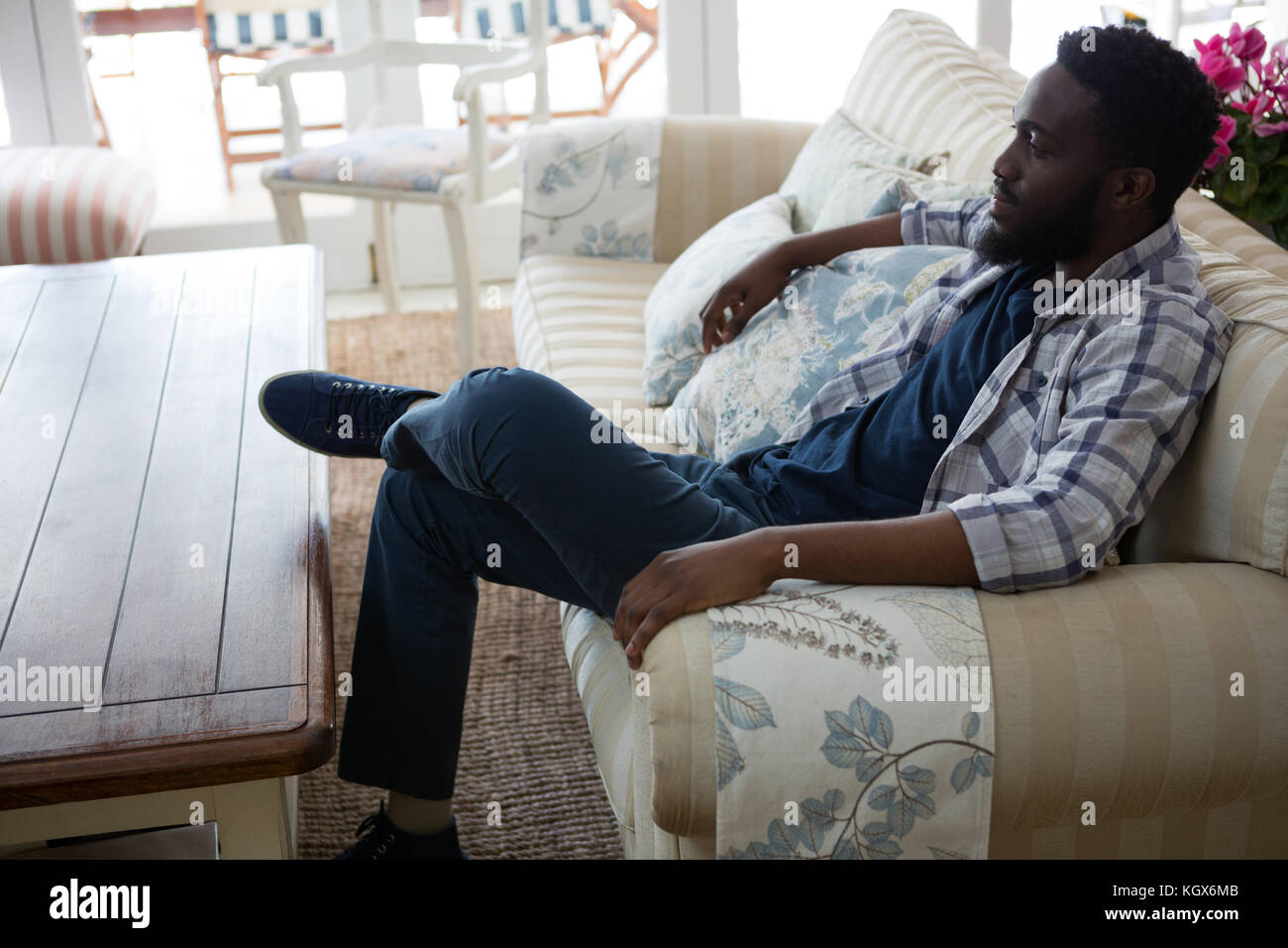Thoughtful man relaxing in living room at home Stock Photo