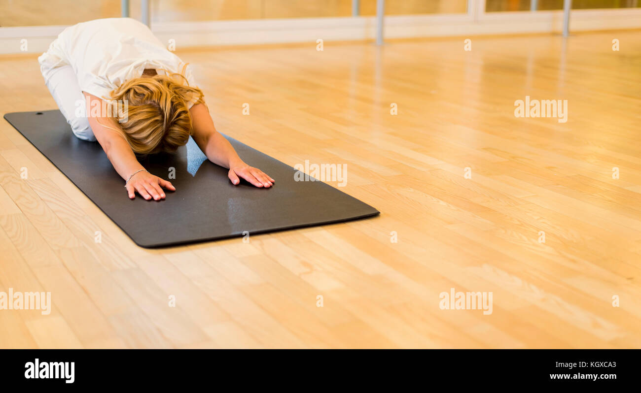 Woman doing Child yoga pose in studio on mat Stock Photo