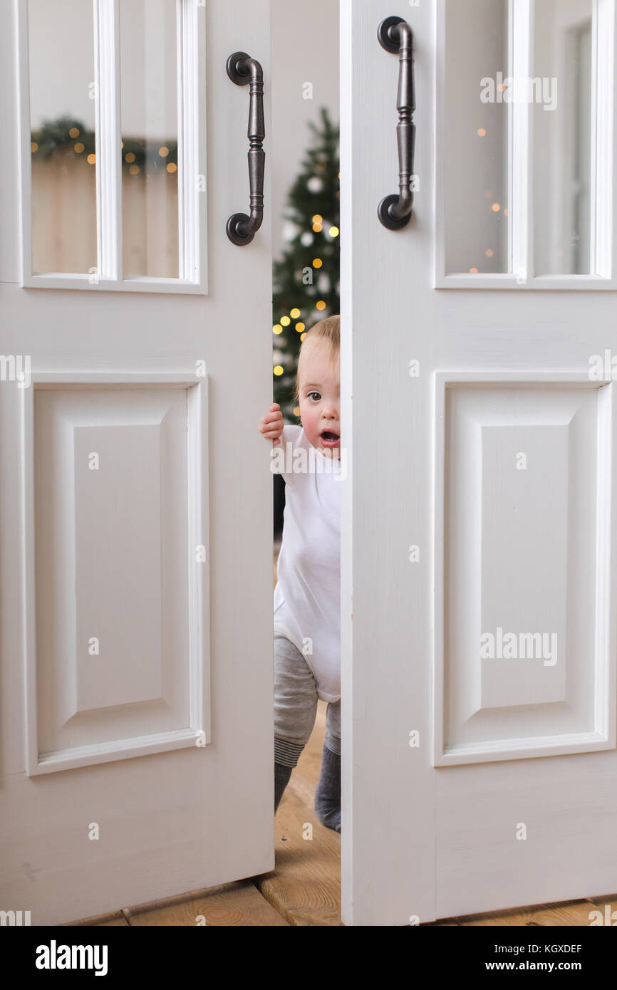 Charming kid opens the door and is surprised Stock Photo
