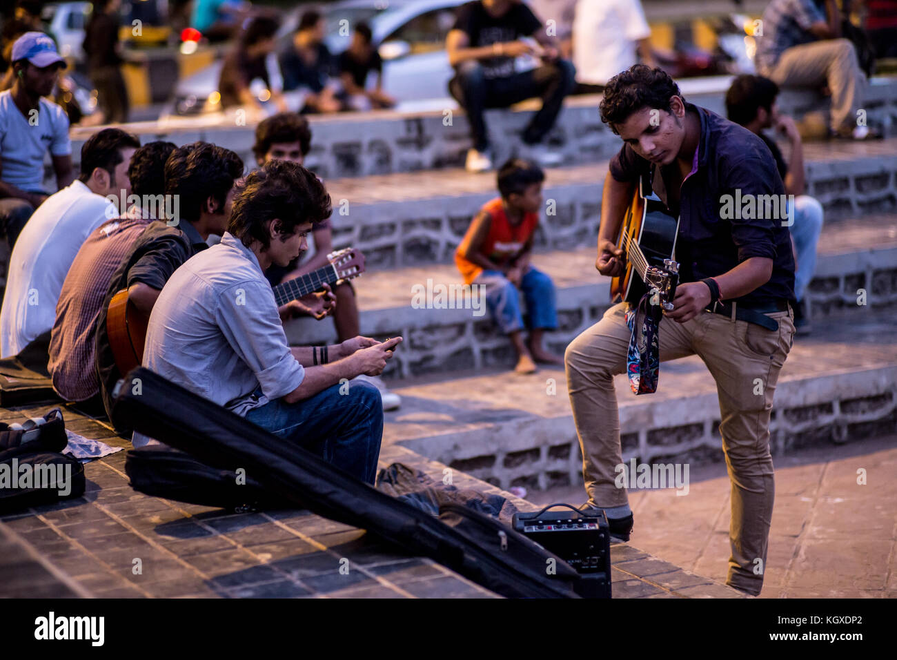 Youth playing music in the evening at a gathering place in Mumbai, India Stock Photo
