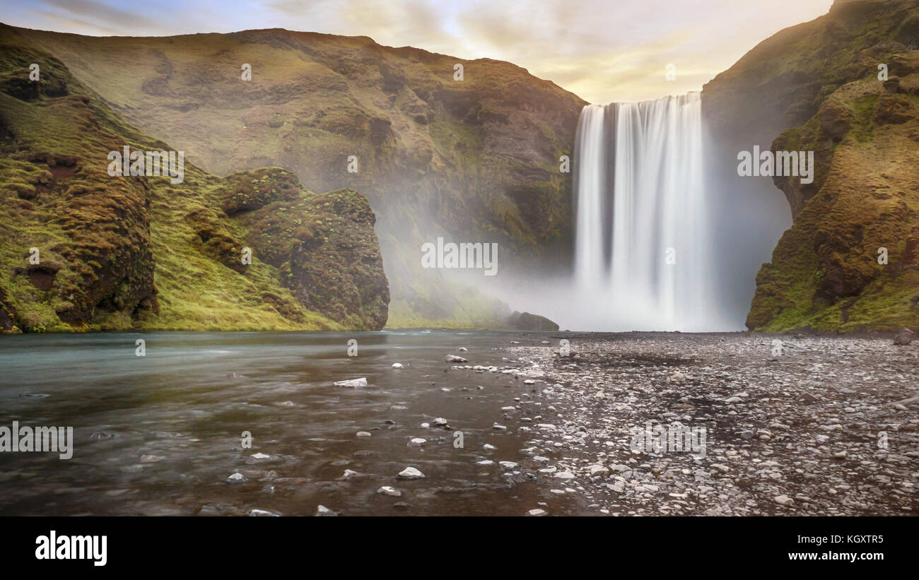 Long exposure of beautiful Skogafoss waterfall with spray over dramatic land. Pastel sky gives soft light. South Iceland. Stock Photo