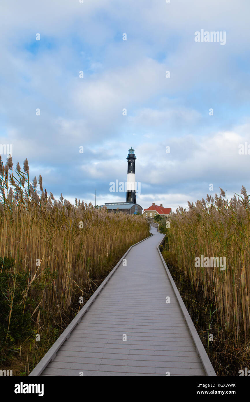 A long wooden road leads to the lighthouse on the coast Stock Photo