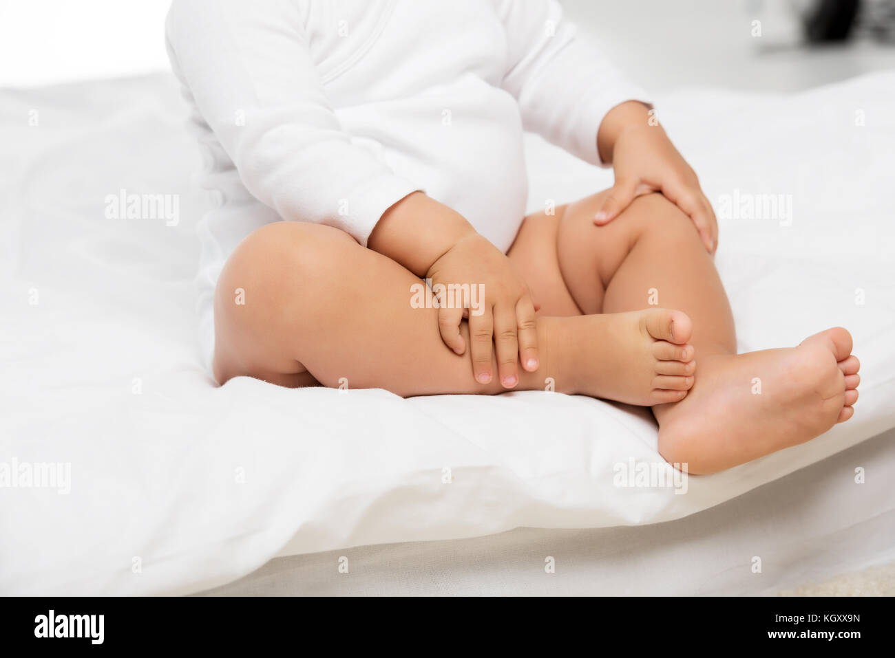 baby sitting on bed Stock Photo
