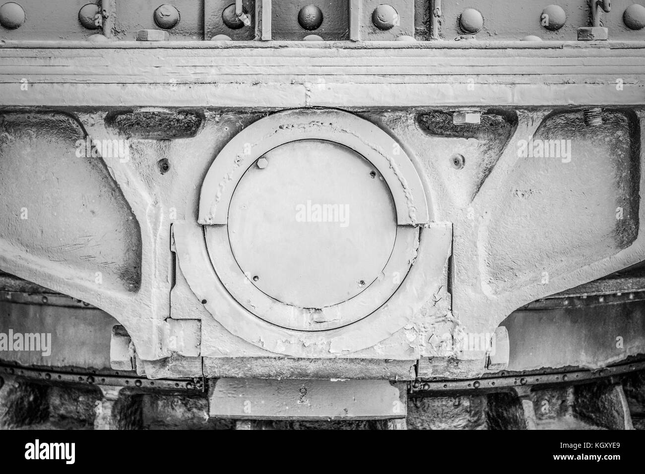Grey painted solid metal frame with bolts and a large axle in the centre. Black and white image. Stock Photo