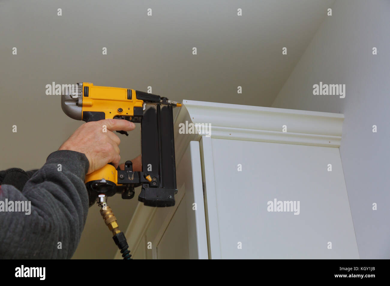 Carpenter brad using nail gun to Crown Moulding on kitchen