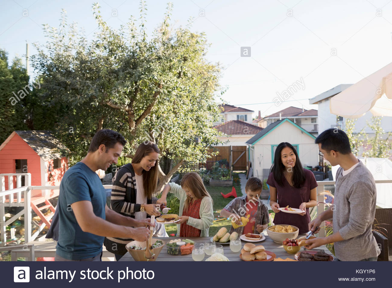 Neighbor families enjoying backyard barbecue potluck Stock Photo