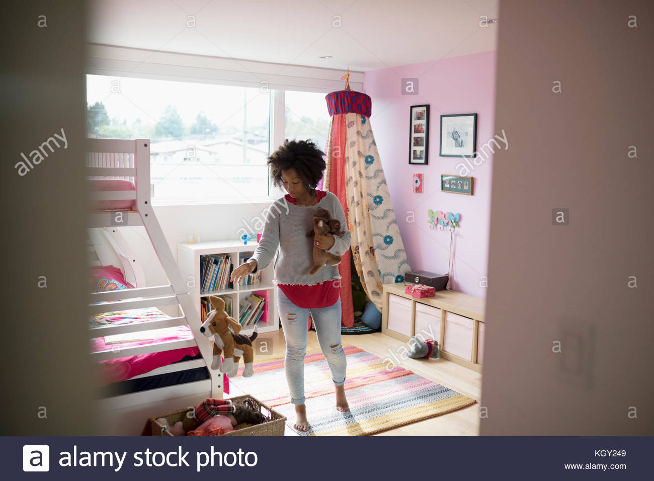 Woman cleaning girls bedroom, putting stuffed animals in basket Stock Photo Alamy