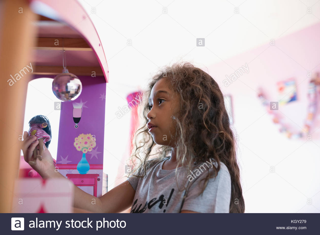 Girl playing with doll at dollhouse Stock Photo - Alamy