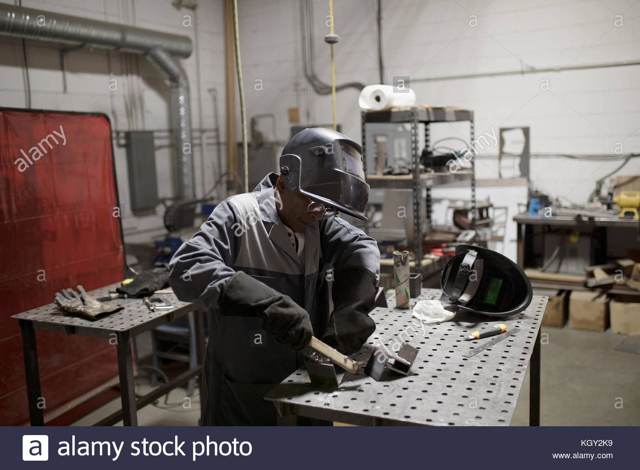 Welder in welding mask working at workbench Stock Photo