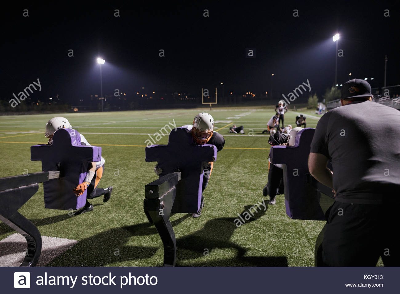 Teenage boy high school football team practicing drills on football