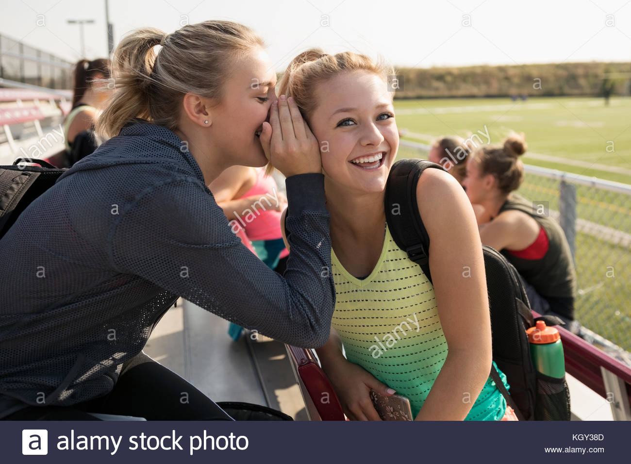 Teenage girl high school cheerleaders whispering, gossiping on