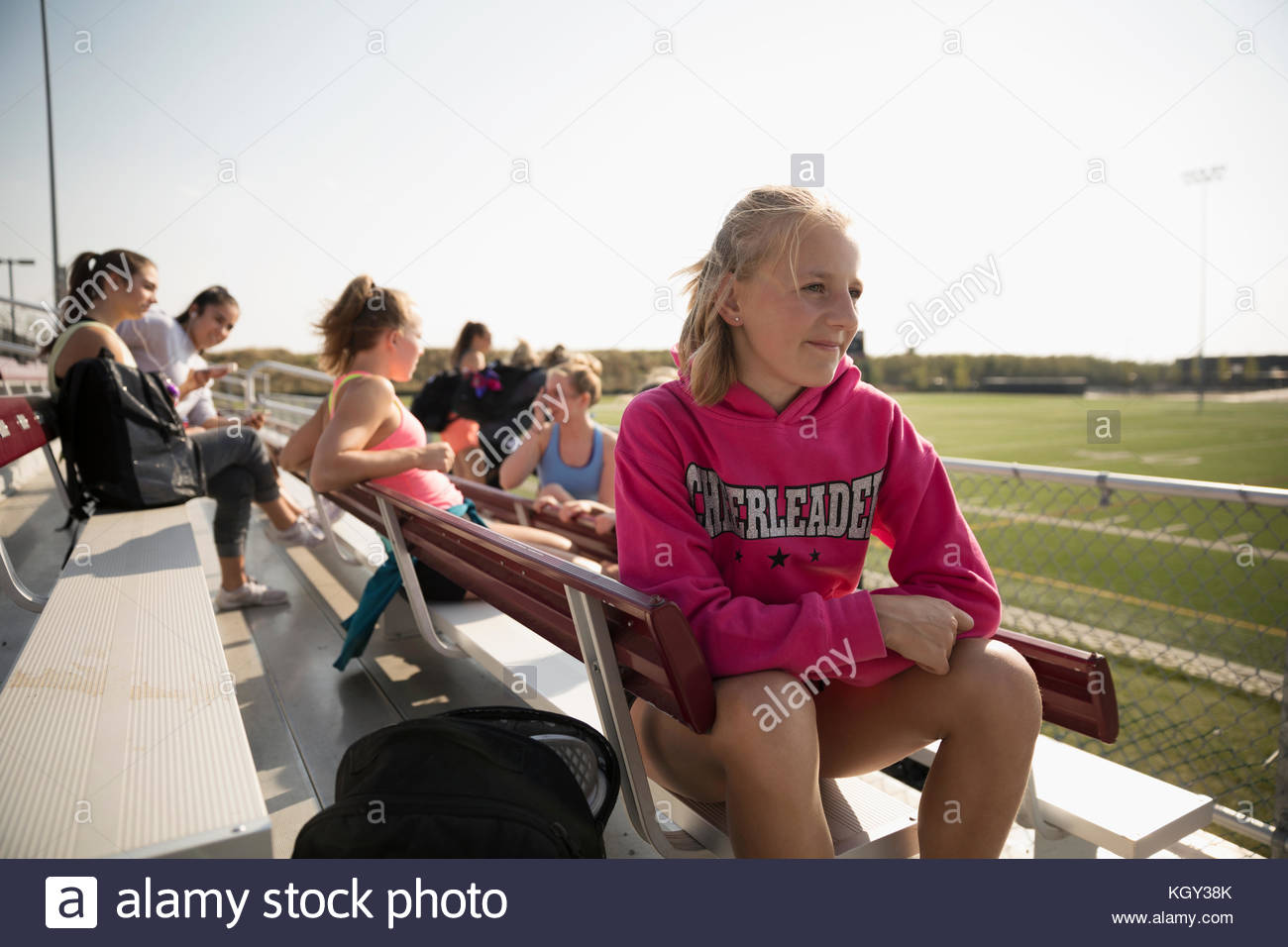 Teenage girl high school cheerleader sitting and looking away on sunny