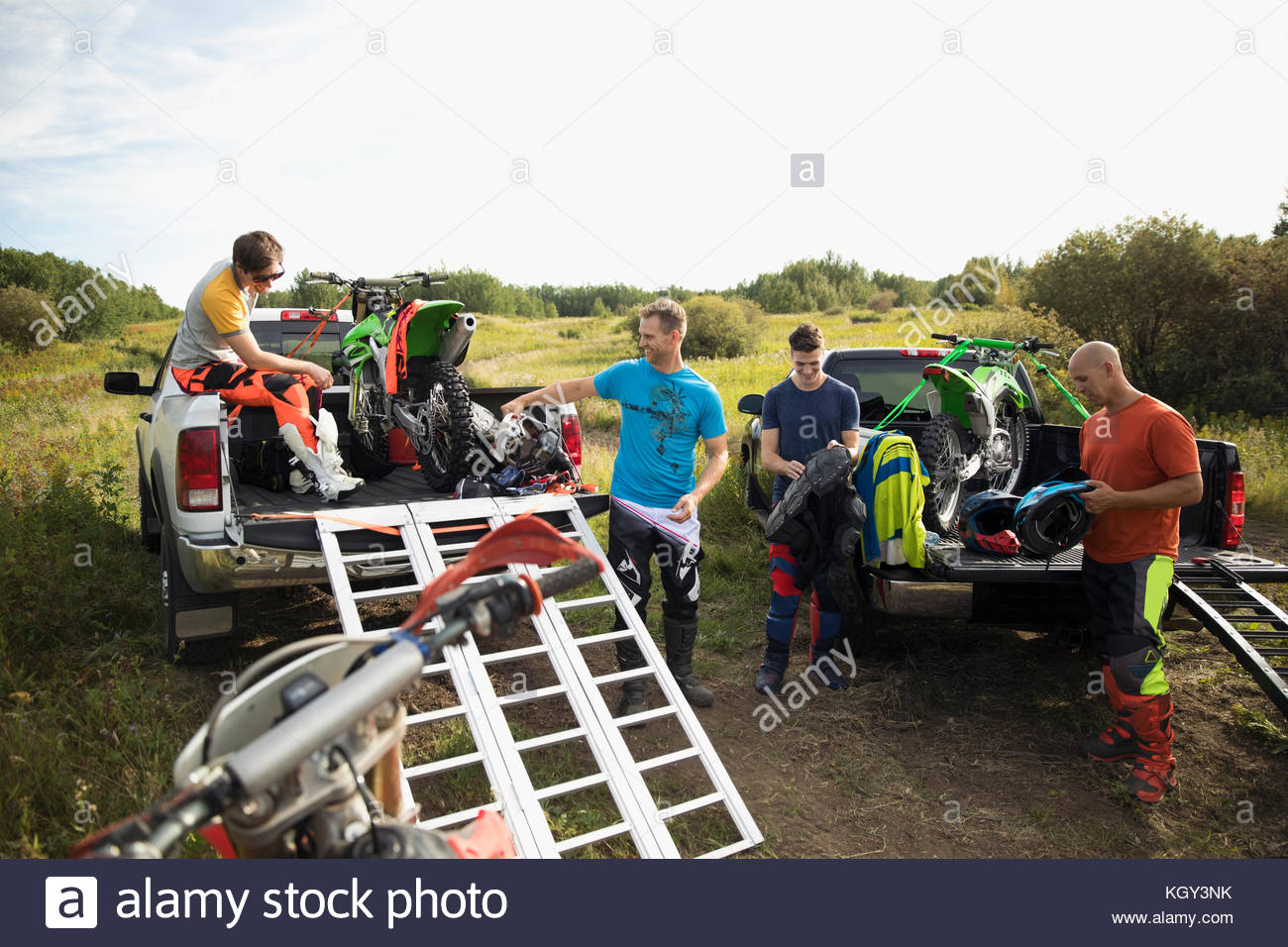 Men unloading motorbikes on trucks in rural field Stock Photo